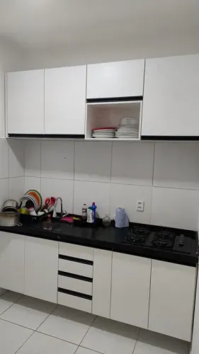 Cozinha projetada toda branca com puxadores gola lá cor preto.