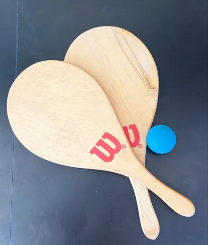 Kit de Frescobol Wilson com raquetes de madeira clara e uma bola azul.