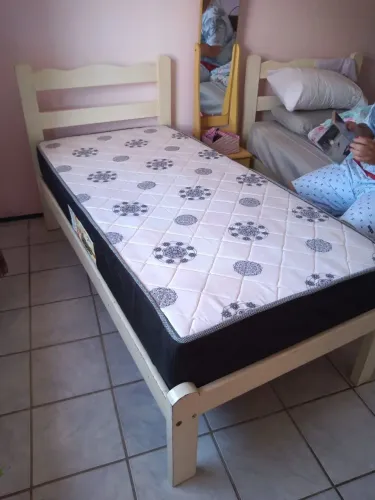 Cama de solteiro de madeira com colchão de mola.