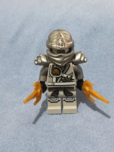 LEGO minifigura Zane (Jungle Robe), com marcas no rosto e um braço trincado