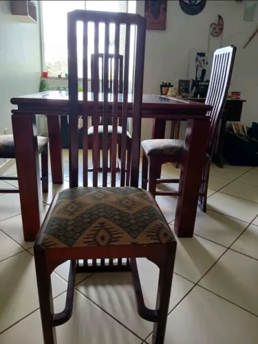 Mesa de madeira com 4 lugares e tampo de vidro, com 4 cadeiras estofadas.