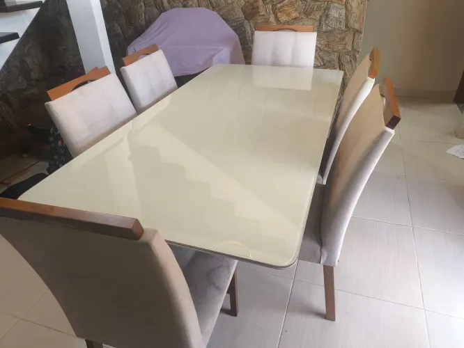 Mesa com tampo de vidro seis lugares com cadeiras acolchoadas e base de madeira