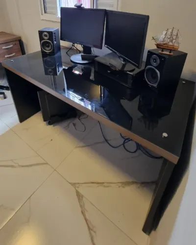 Mesa de escritório com tampo de vidro preto.