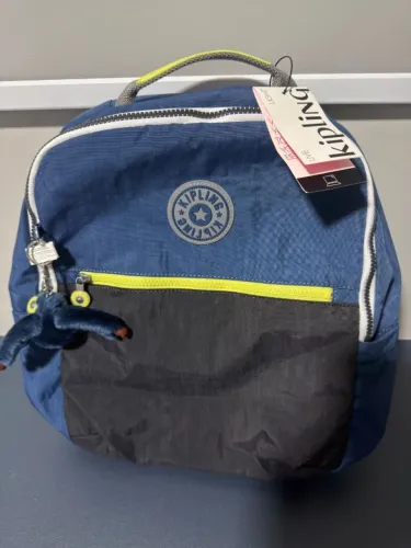 A mochila na imagem é um modelo Kipling Seoul, especificamente na cor azul com detalhes em
