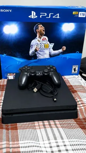 Playstation 4 slim de 1TB com caixa e um controle. Tem uma conta nele com GTA E FIFA 26.