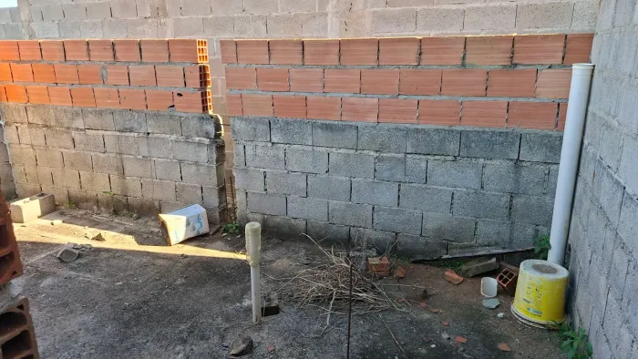 Terreno com 2 metros de alvenaria erguido contra piso e rede de esgoto. Fossa.