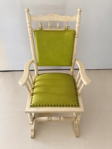 Cadeira de balanço em madeira maciça com estofado verde.