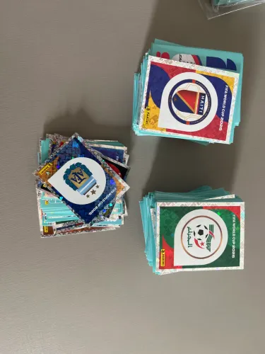 Figurinhas da Copa - 720 total e 460 sem repetição). Escudos e (Mbappe, CR7, Vini)