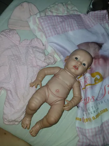 Vendo bebê reborn, com traços realistas, incluindo brincos na boneca e roupinhas