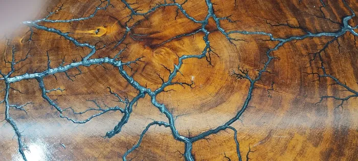 Mesa de centro eletrificada em madeira maciça e resina com veios pretos.