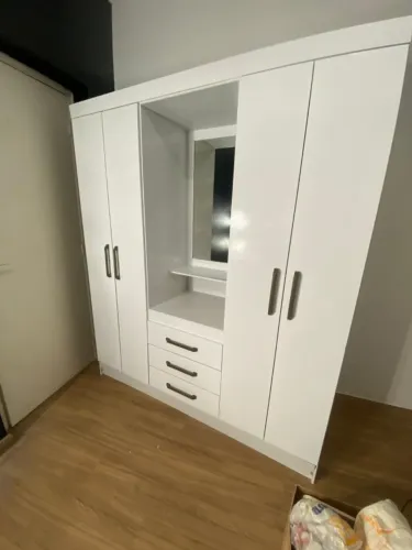Armário branco duas portas com gavetas e espelho central.