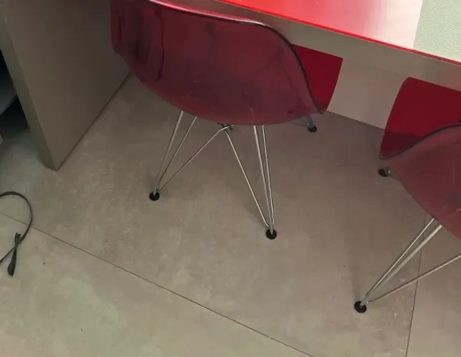 cadeiras lembram o modelo Eames/DSW em policarbonato fumê avermelhado com pés metálicos.