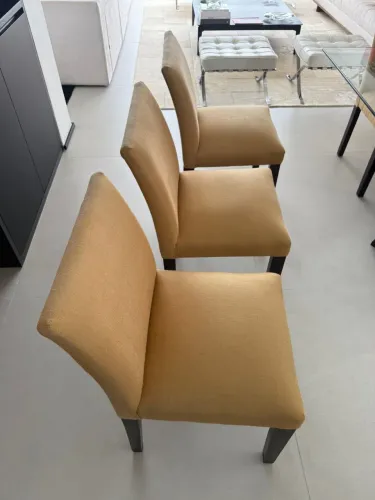 Conjunto com 8 cadeiras de madeira escura, estofadas com tecido de linho na cor mostarda.