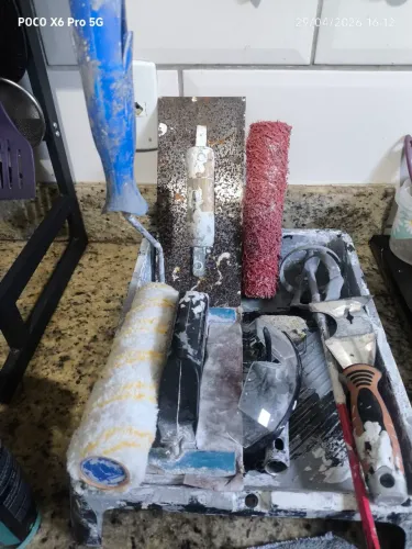 ferramentas de pintura, incluindo caçamba, rolo e desempenadeira. 