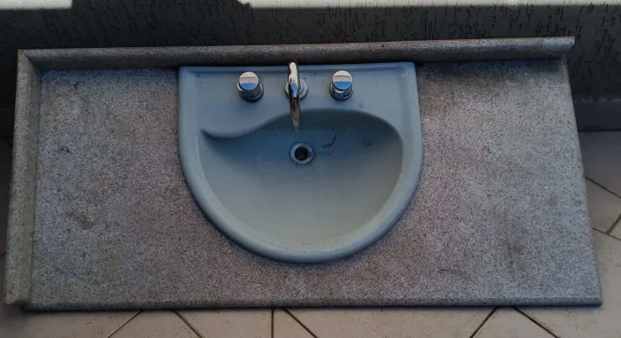 Cuba de pia de cerâmica azul clara com bancada em granito combinando