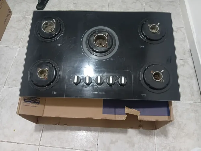 Fogão de 5 bocas com mesa de vidro preta.