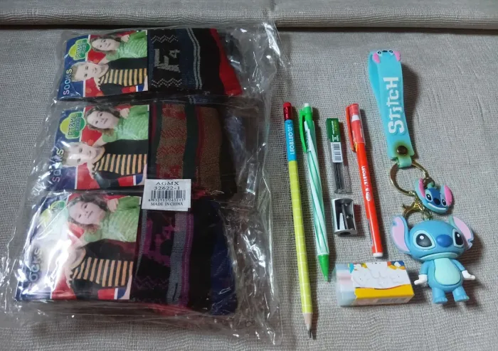 Pacote com doze pares de meias unissex, chaveiro Stitch e peças escolar variadas.