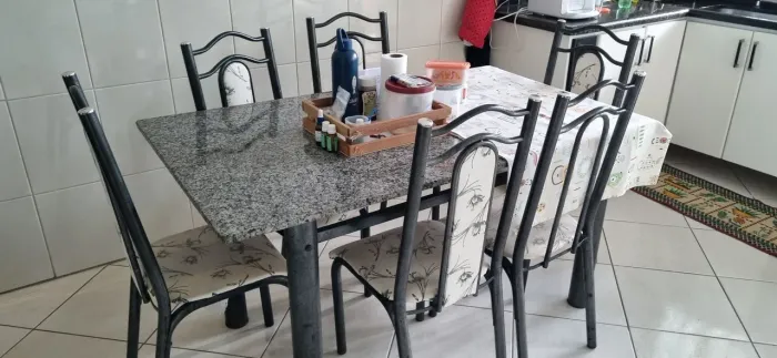 Linda mesa de jantar com tampo de granito e estrutura em metal, acompanhada por 6 cadeiras