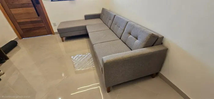 Sofá cinza de 4 lugares com chaise e pés em madeira