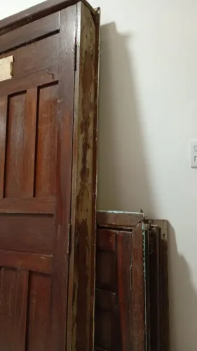 Porta antiga de madeira maciça com caixa caracterizada por painéis almofadados e um acaba