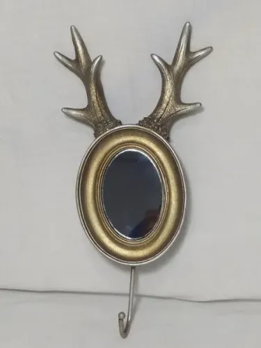 Elegante espelho de parede representado por par de chifres de alce e com gancho para roupa
